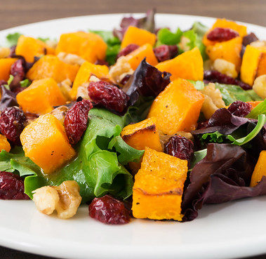 Autumn salad with roasted butternut squash, cranberry and walnuts on white plate, selective focus, horizontal